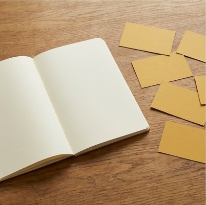 AI-generated editorial illustration: open notebook and small mustard cards.