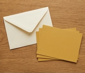 AI-generated editorial illustration: cream envelope and blank mustard cards.