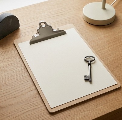 AI-generated editorial illustration: blank clipboard beside a metal key.