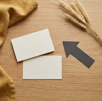 AI-generated editorial illustration: two blank cards beside a charcoal paper arrow.
